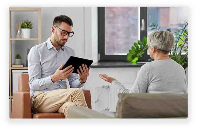 Woman speaking with therapist who is using a tablet to take notes